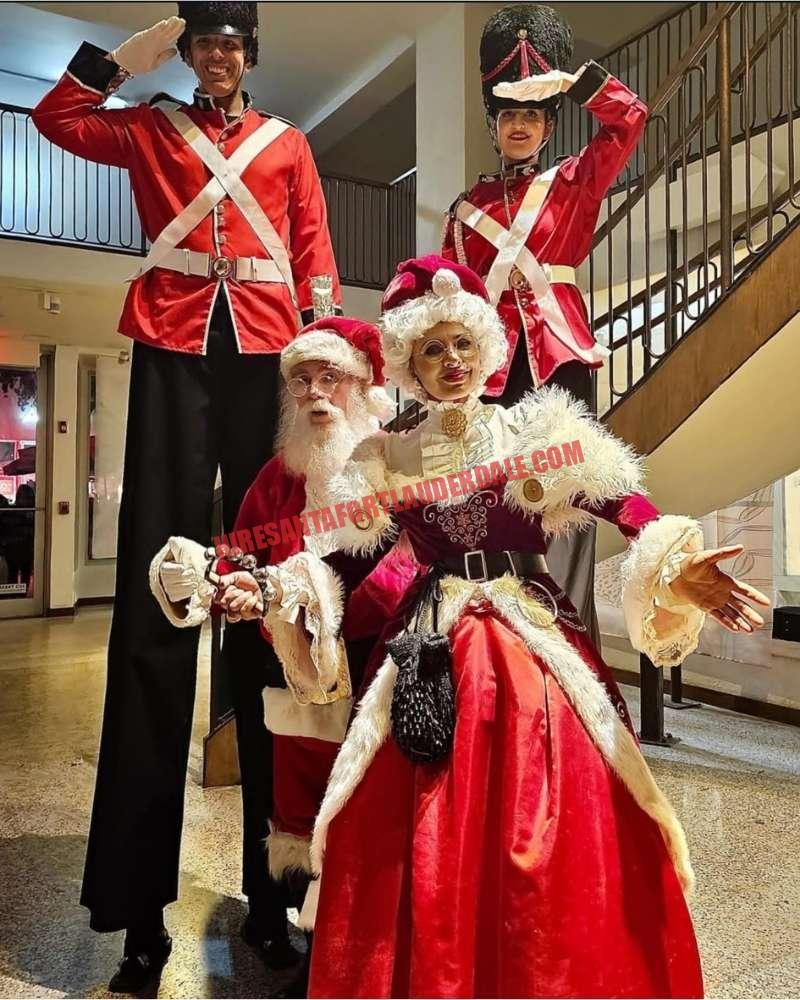 Corporate Santa in Fort Lauderdale with two stilt nutcracker soldiers and Mrs. Claus indoors
